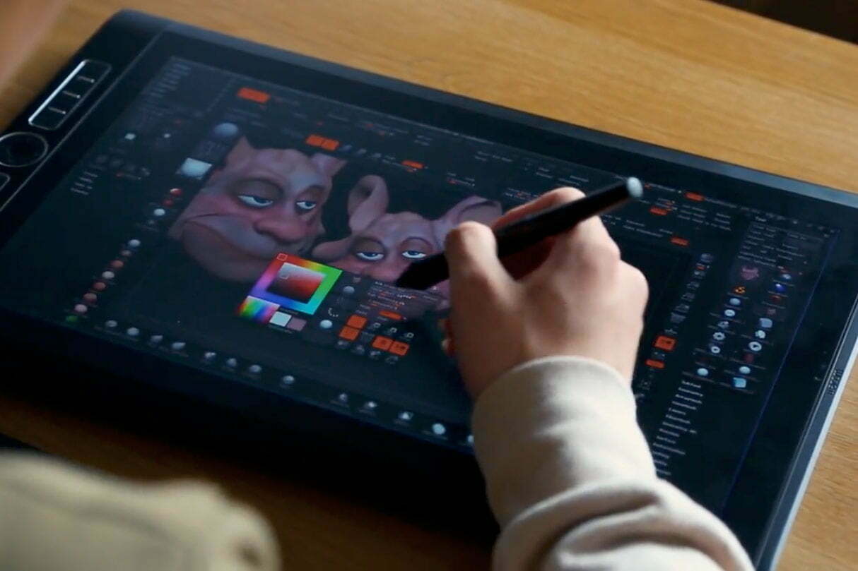 Artista 3D modelando em um monitor interativo.