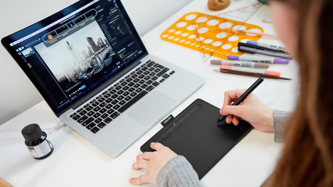 Designer usando uma mesa digitalizadora conectada a um notebook por bluetooth.